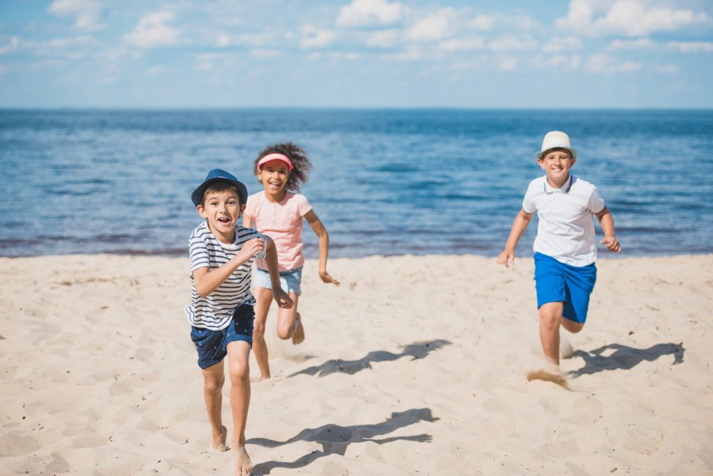 Multicultural group of little children playing together on beach